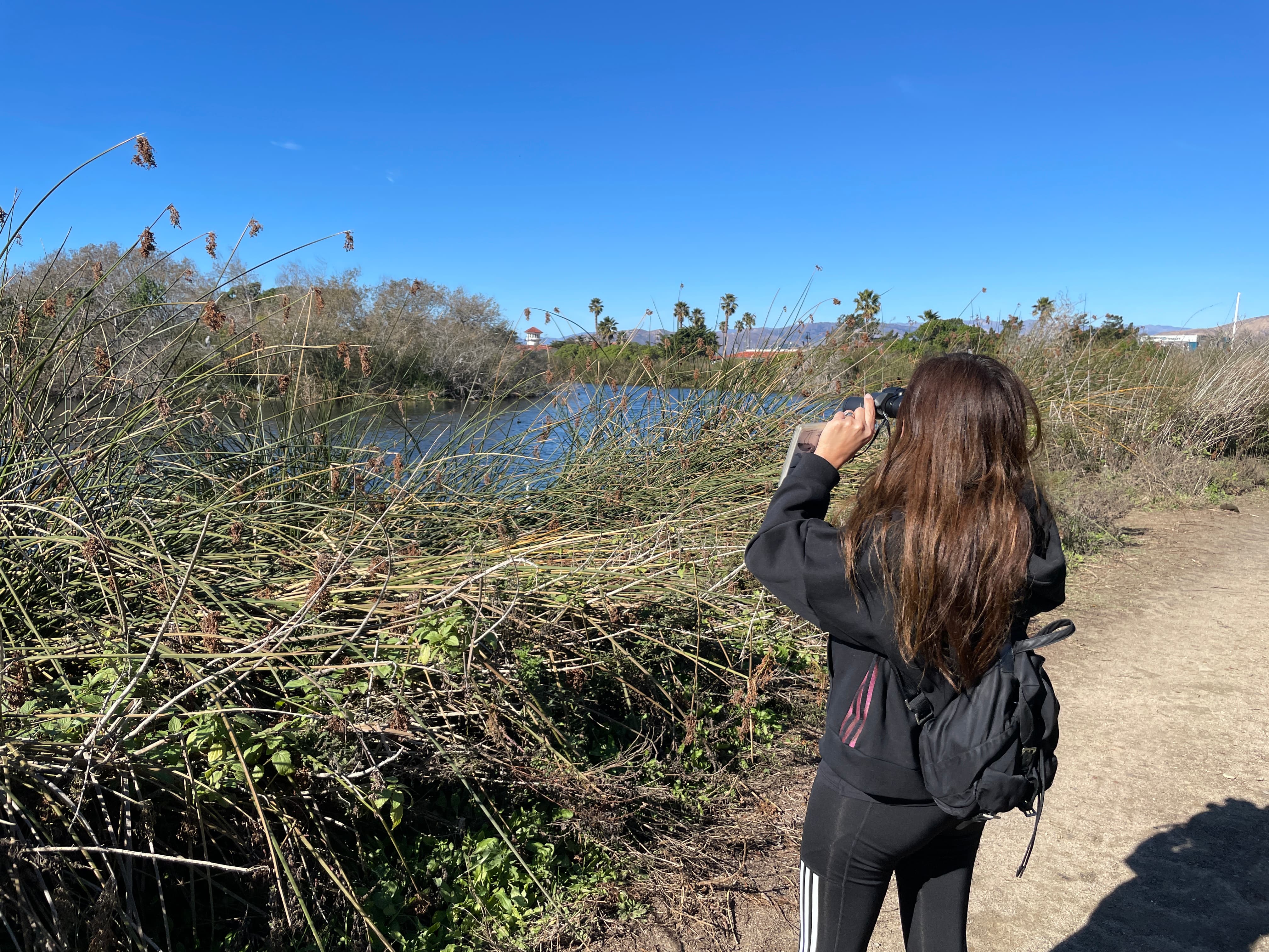 woman bird watching near river