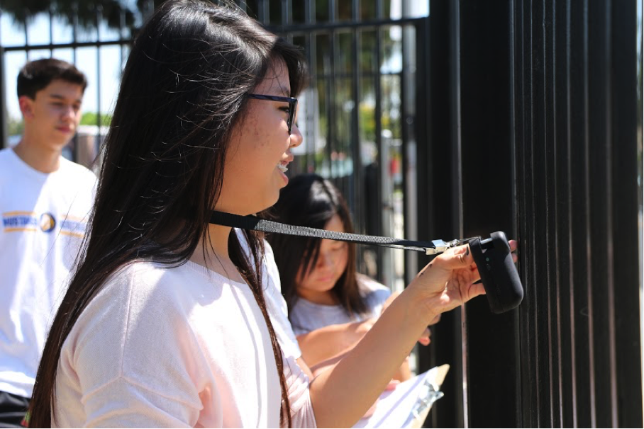 A person holds a black sensor up in the air
