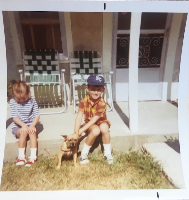 Two kids and a dog sit on a porch