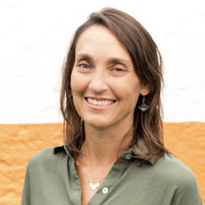 Nicole Swedlow smiles in front of an orange sand dune wearing an olive button up shirt