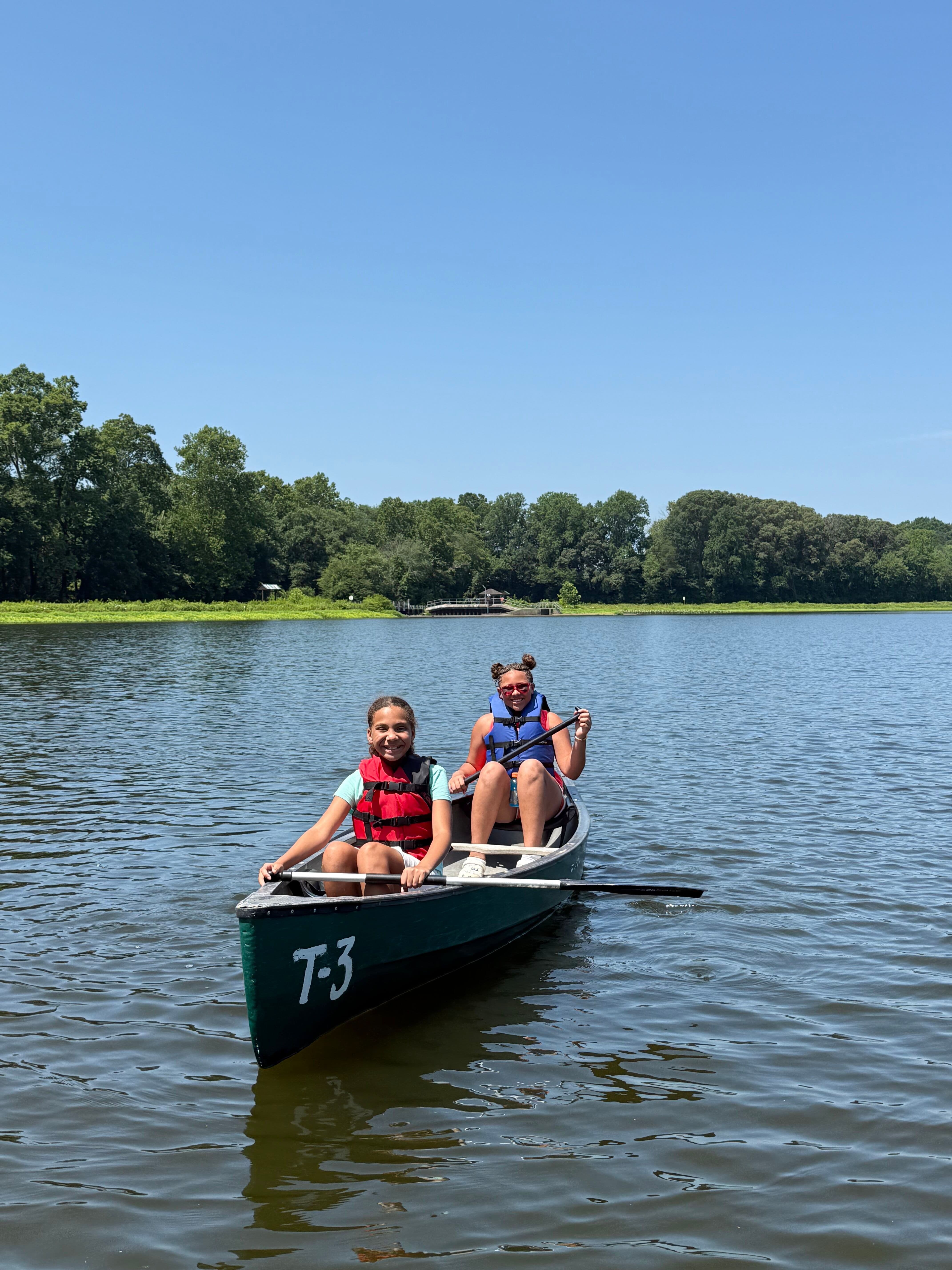 Two students paddle in a canoe on a lake