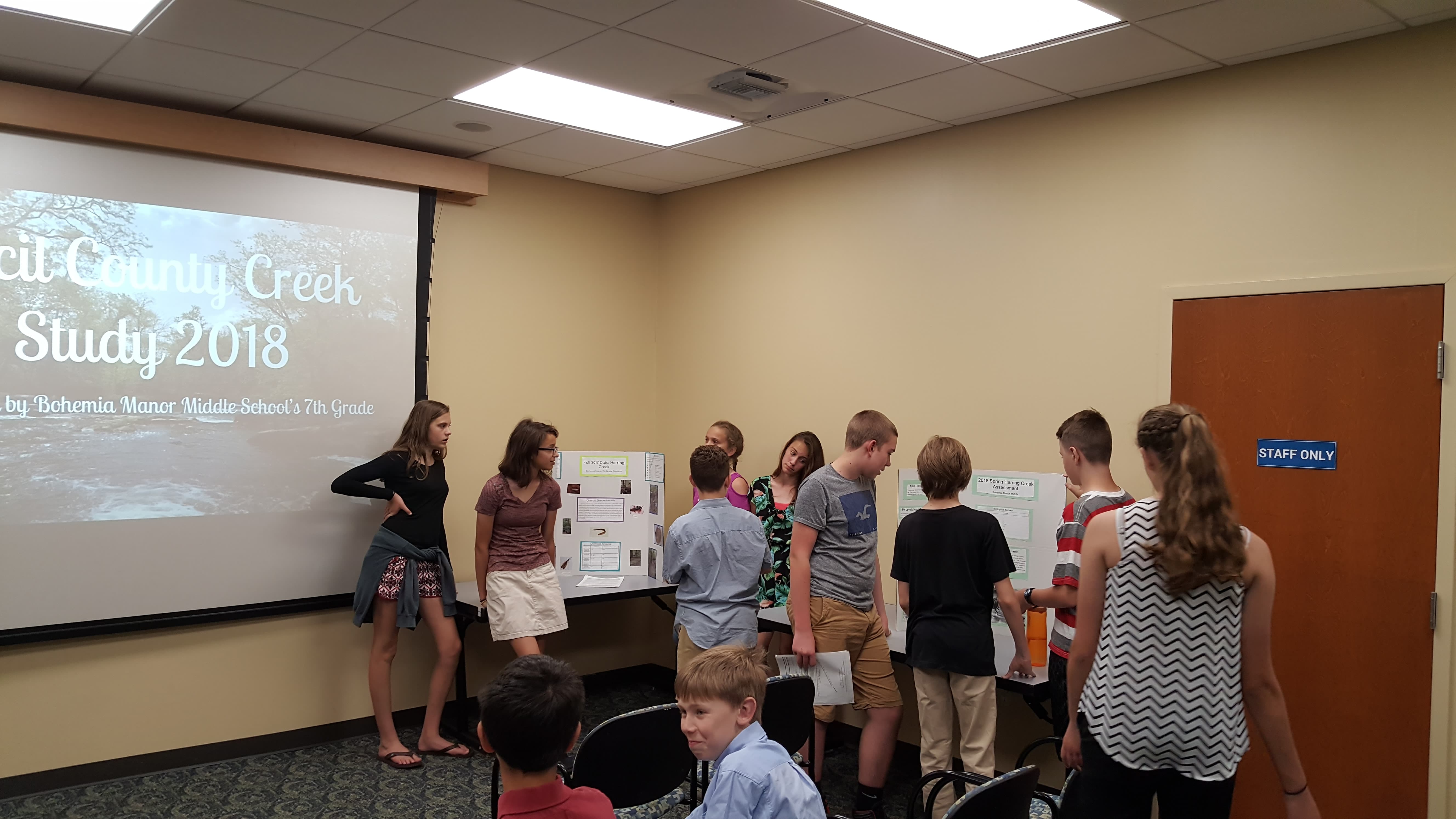 Students present on behavior changes community members can make to improve local water quality at a public event