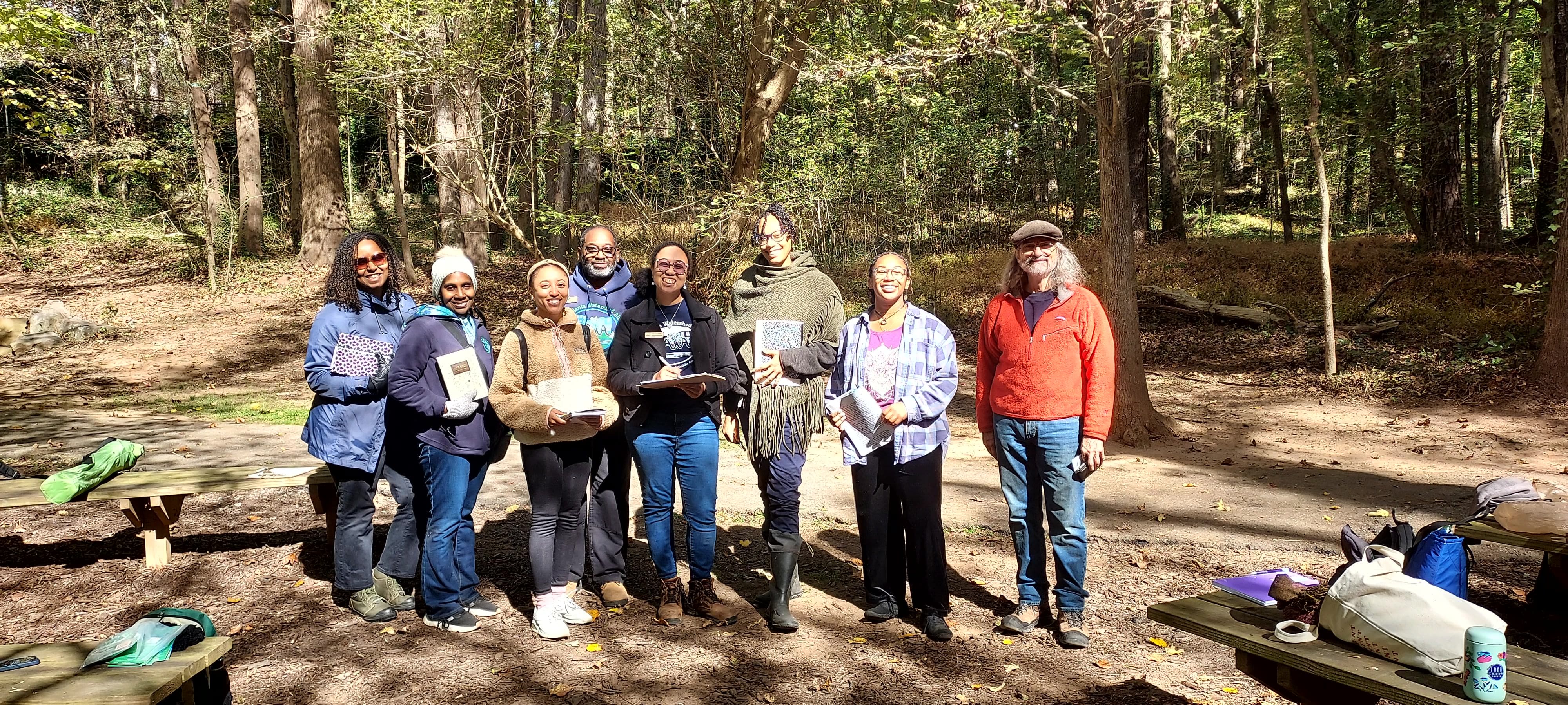 In a forest, a group smiles at the camera