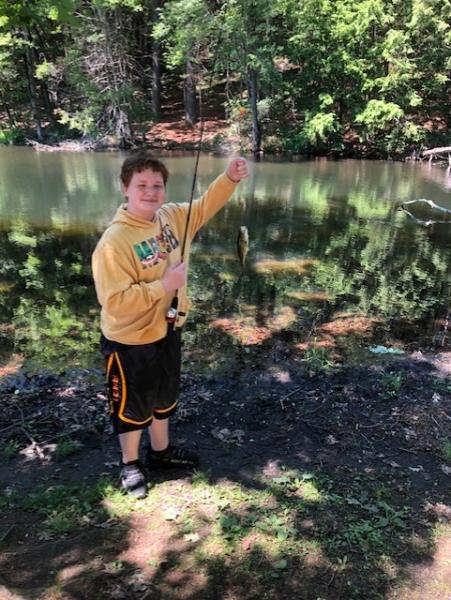 A student holds up a fish caught near the river.