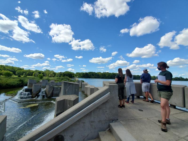 Four adults look out over a constructed dam from a decorative concrete platform Credit: Autumn Mitchell, FRWC