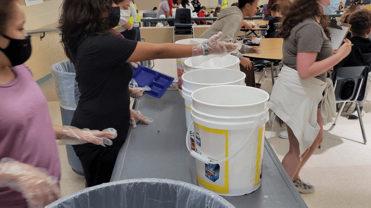 Students reach to collect leftover lunches from their peers at Prairie View Middle School