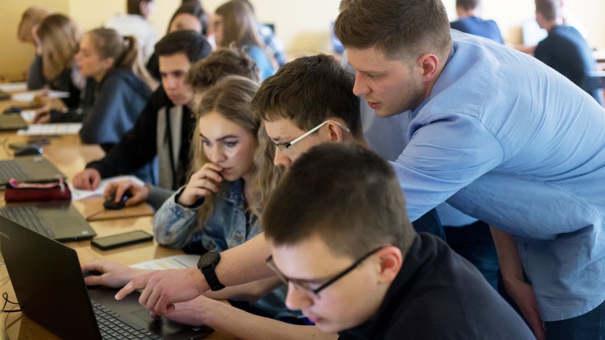 An instructor helps students learning at their computers. 