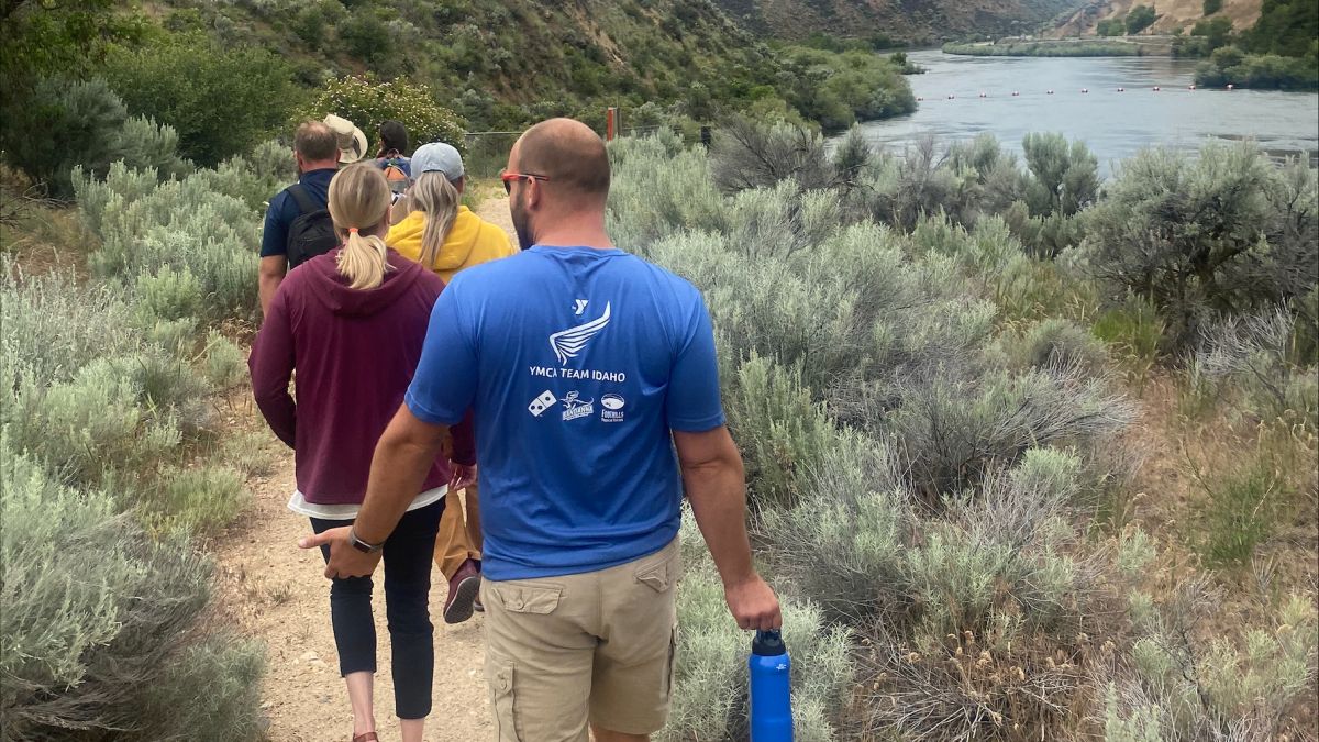 A group walks along a path between a mountain and a riverbank. Photo credit: Janice Alexander