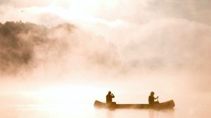 Two people in a canoe on a lake on a misty day
