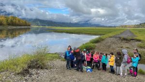 Author Jade with a group of children near a lake and with mountains in the back.
