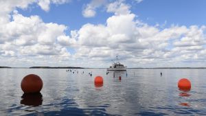 A lone boat out on the water with three red buoys