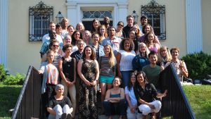 group of ee360 Fellows standing and sitting on stairs in front of yellow building