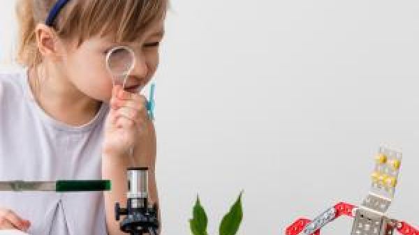 Young student scientist using a magnifying lens to examine a plant.