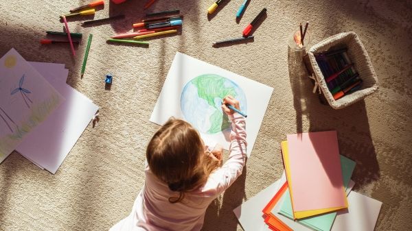 Child uses coloring pencils to draw Earth
