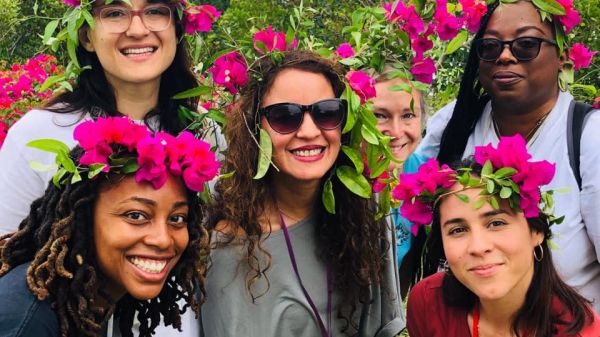 Photo of six people with pink flowers in their hair.