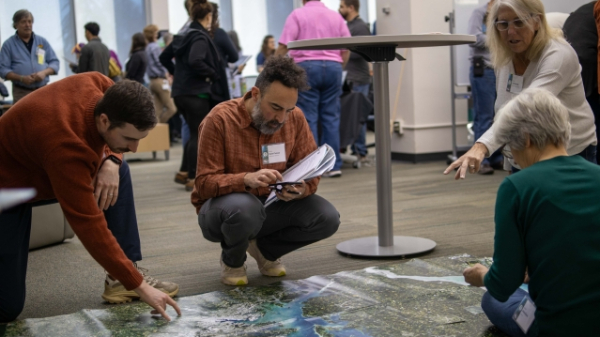 Four Earth to Sky participants take notes and point at a large Landsat map on the ground.