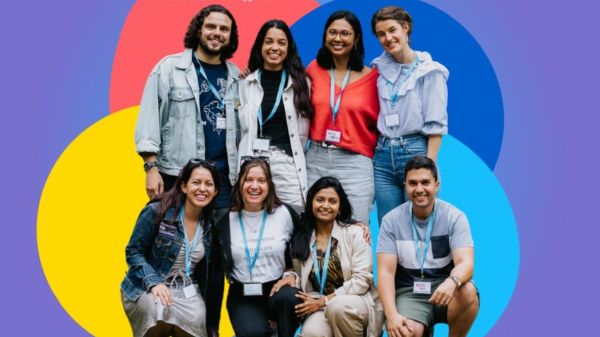 Group of smiling students in fron tof four colorful overlapping circles set against a purple background