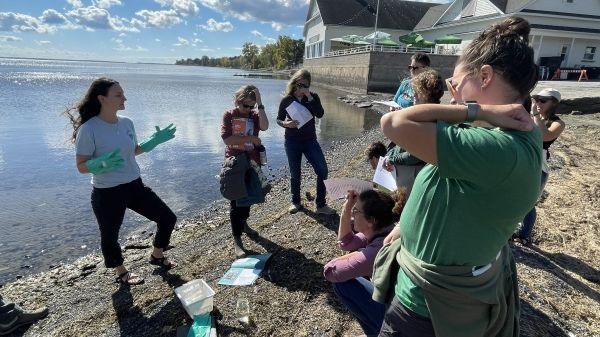 A group of teachers watching an instructor on the lakeshore