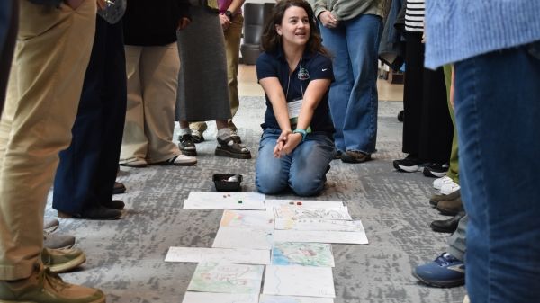 The image shows an educator in the middle of a crowd teaching