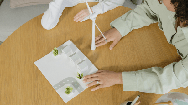 Environmental Education Two people sit at a table with a paper town and miniature wind turbine
