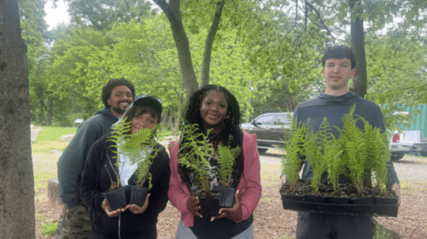 Future Leaders of Our Waters Fellowship Program graphic with a group of students in the background. Three students hold plants from a service project.