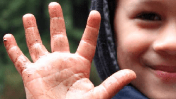 child holding up muddy hand