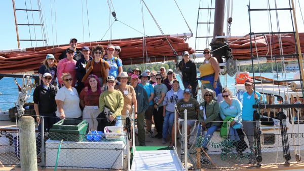 2024 GLWFC Teacher Cohort A group of teachers smile while sitting on the deck of a tallship schooner.