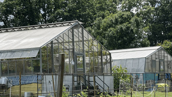 Great Kids Farm Photo of two greenhouses and a garden, with a fence in the foreground.