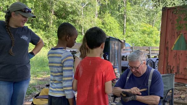 Image of two children observing an adult at forest school