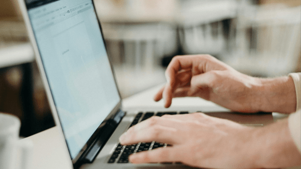 Join the Sustainability Policy Partner Initiative listserv Two hands type on a laptop on a white table; white chairs can be seen in the blurred background