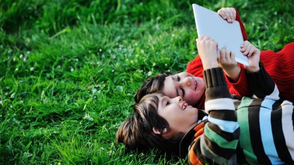 Two young children laying in the grass looking up