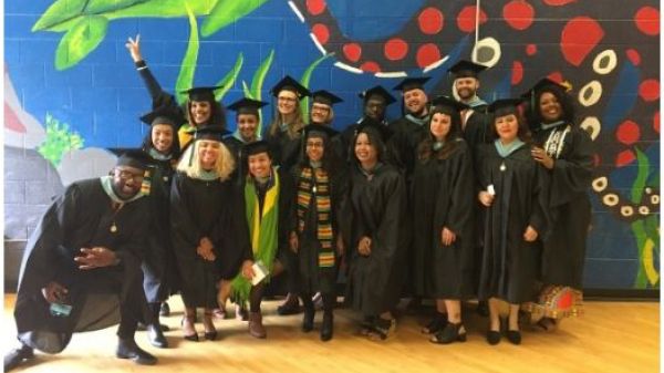 group of graduates in black robes and caps in front of colorful mural