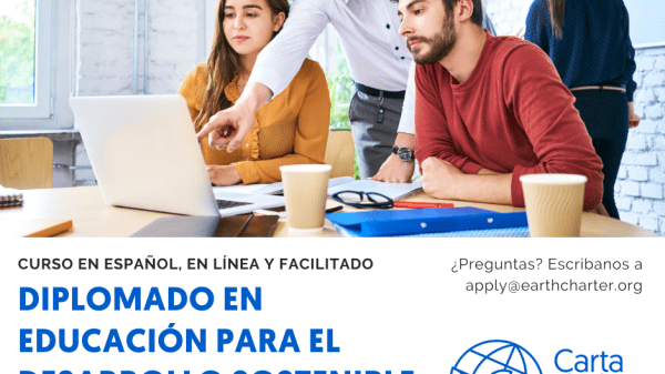 Instructor stands between two students, pointing at a computer screen