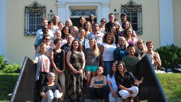 group of ee360 Fellows standing and sitting on stairs in front of yellow building