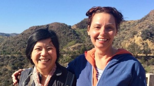Two people smiling toward the viewer with a California landscape in the background