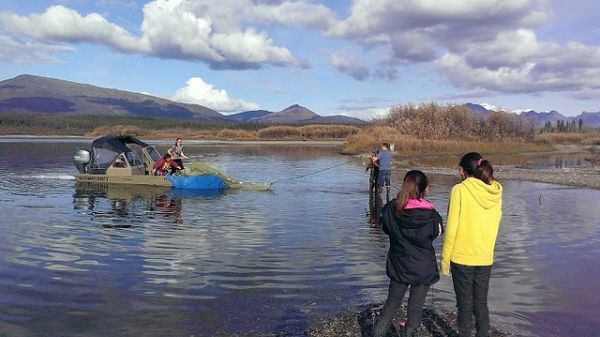Two kids at the beach watch a boat pull onto a shallow beach