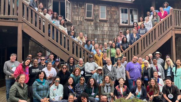A group of WTRE participants standing in front of a wooden building for a group photo
