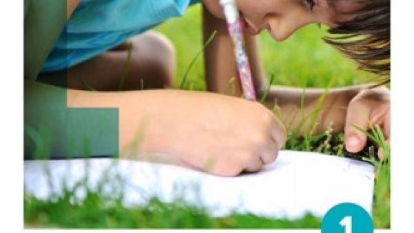 A young child writing on paper lying on grass