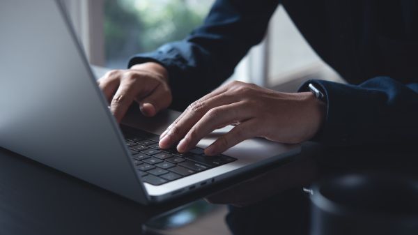 Typing on Keyboard Two hands type on a laptop keyboard