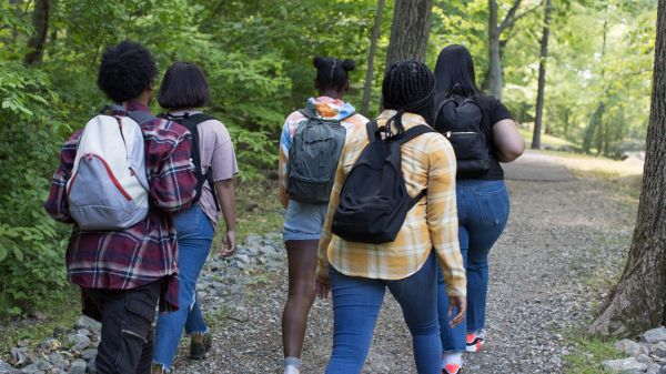 Group of five teenagers walking on a forested path