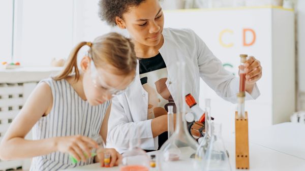 A child and adult stand behind a table full of test tubes and beakers