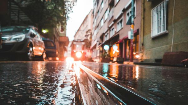 A low view of a city street with water, cars running along it