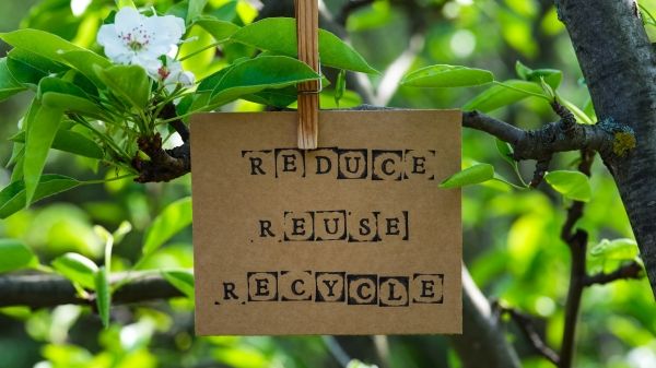 A piece of paper clipped to a tree that reads "Reduce, Reuse, Recycle"