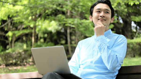 Person on bench, trees in background, laptop.
