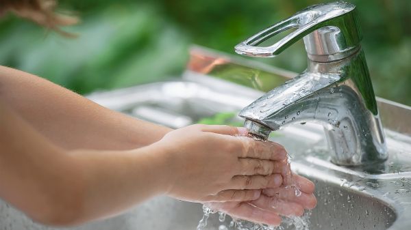young child's arms and hands washing under faucet