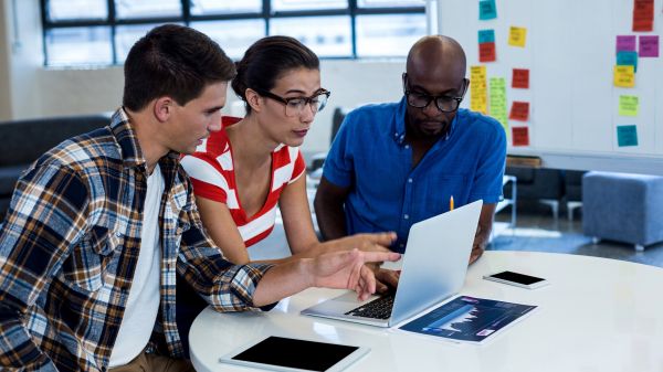 three people looking at computer in office