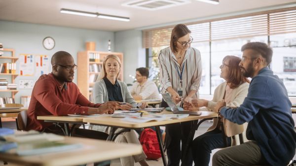 Teachers gather around a table reviewing and interacting with educational materials