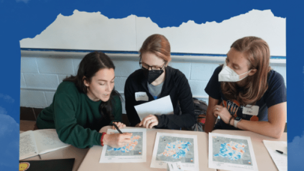 Three people, two of which are in masks, review maps of air quality data.