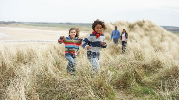 young kids with adults running through grass
