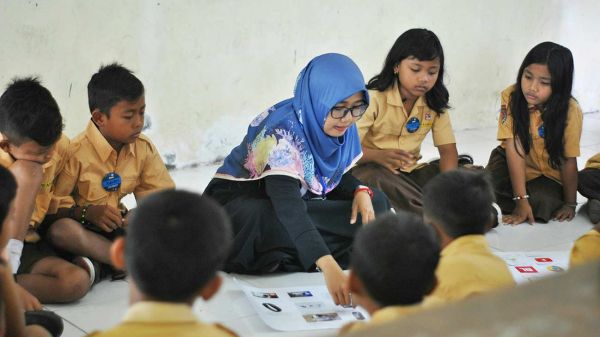 World Food Forum Educators Network A group of children and an adult, who appears to be a teacher, are sitting on the floor in a classroom setting.